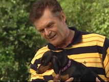Fred Willard holds a "hot dog" in the Disneypedia featurette "Going to the Dogs."