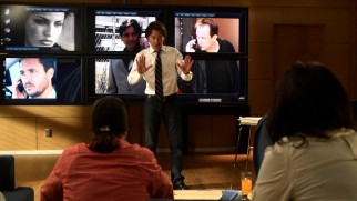 Nate stands in front of his bank of TV screens, which here depict the con artist team his is evenly matched with. Can you spot '80s icons Wil Wheaton and Griffin Dunne?