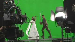 Bridget Regan and Craig Horner pose for publicity shots in front of a green screen in "Forging the Sword: Crafting a Legend."