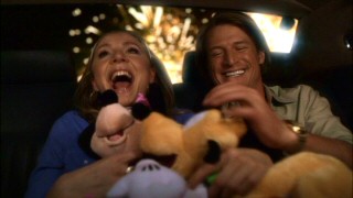 With fireworks going off behind them, Clarissa (Sarah Chalke) and Aaron (Philip Winchester) enjoy their newly-acquired Minnie Mouse and Pluto plush dolls. Little does she know he's got a whole room of plush dolls.