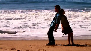 Joe Jonas and Demi Lovato lean back on each other in their "Make a Wave" beach music video. I guess he's taller.