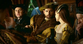 King Henry VIII (Eric Bana) leans in and takes interest of Anne Boleyn, while The Duke of Norfolk (David Morrissey) looks on.