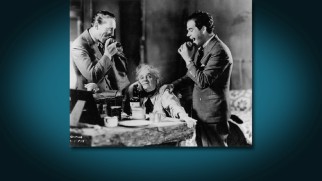 Warren William and director Frank Capra prepare to bite apples in the presence of Apple Annie (May Robson) in this behind-the-scenes photo gallery still.
