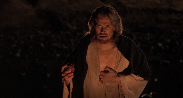 Jesus Christ (Willem Dafoe) pulls his bleeding sacred heart from his chest to present it to his followers as a way to convey the importance of love.