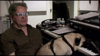 While Mark Mothersbaugh discusses his Wes Anderson scores, Mothersbaugh's dog rests his head on a keyboard.