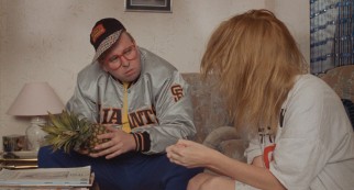 Nicola watches as boldly-fashioned family friend Aubrey (Timothy Spall) fidgets with a pineapple.
