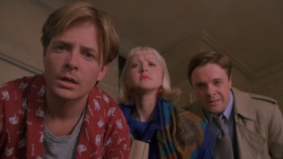 Chapman (Michael J. Fox), Chapman (Nathan Lane), and their receptionist Geena (Cyndi Lauper) evaluate their client's black and blue the morning of her big commercial shoot.