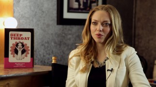 Next to a small "Deep Throat" poster, a blonde, freckle-less Amanda Seyfried discusses playing Linda Lovelace, her first real character.