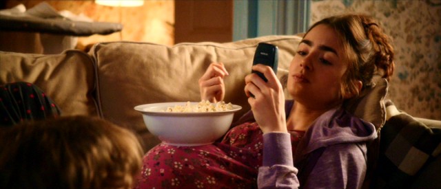 Rosie (Lily Collins) uses her pregnancy bump to balance a bowl of popcorn in "Love, Rosie."