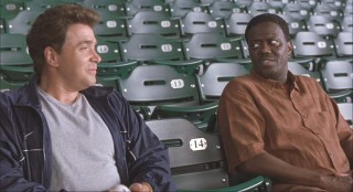 Stan and his best friend Boca (Michael Rispoli) sit in emptied bleachers.