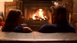 Reba (Erin Karpluk) and Seth (James Van Der Beek) get cozy in front of the fireplace, as lovers are known to do at Christmastime.