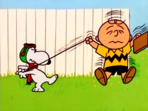 Flying Ace Snoopy reminds Charlie Brown who's in control with a "play dead, then yank the leash" trick.