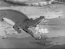 Little Swee'Pea gets dangerously close to a crocodile's open jaw at the zoo.