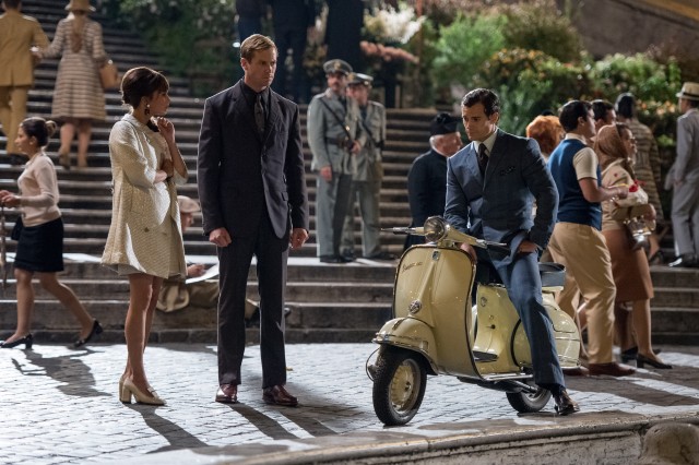 Napoleon Solo (Henry Cavill) coaches Gaby Teller (Alicia Vikander) and Illya Kuryakin (Armie Hammer) on how to act like an ordinary engaged couple.