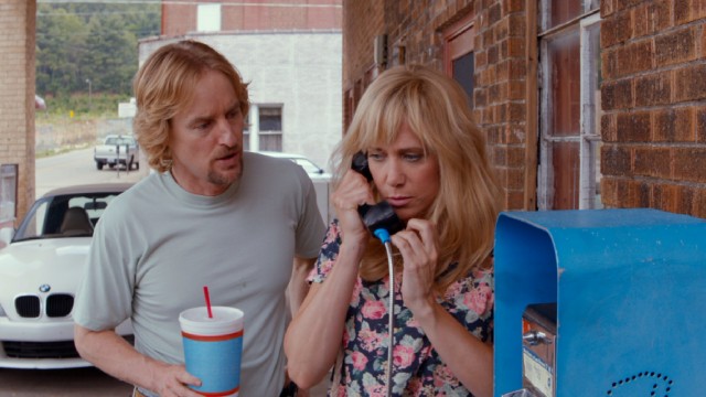 Steve Chambers (Owen Wilson) listens in while Kelly Campbell (Kristen Wiig) catches up with the Mexico-fled David using something called a pay phone.