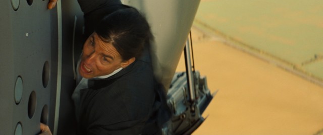 Ethan Hunt (Tom Cruise) clings to the side of an in-flight airplane in the dynamic opening sequence of "Mission: Impossible - Rogue Nation."
