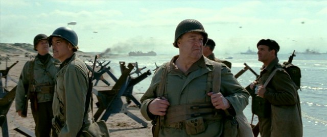 The Monuments Men (including Bill Murray, George Clooney, John Goodman, and Jean Dujardin) reach the shore at Normandy Beach.