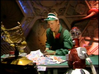 Crow T. Robot keeps hitting in the episode-opening game of blackjack dealt by Mike Nelson (Michael J. Nelson).