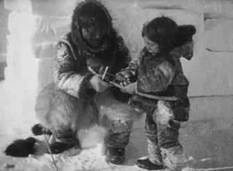 Nanook of the North teaches his young son how to use a bow and arrow.