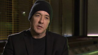 A beanie keeps John Cusack's head warm as he speaks in "The Making of 'The Numbers Station.'"
