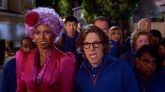 Jackie Joyner-Kersee (Toks Olagundoye), dressed as The Hunger Games' Effie, and Larry Bird (Simon Templeman) brace themselves for the Halloween-ween invaders they have been told are harmless trick-or-treaters.