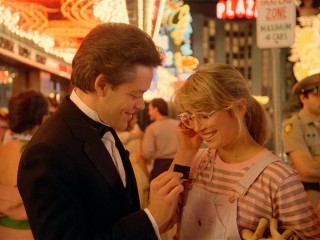 Suave Ray (Raul Julia) hands Frannie (Teri Garr) a matchbook to the club where he is a singer/pianist/waiter.