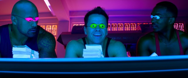 The three bodybuilders/criminals (Dwayne Johnson, Mark Wahlberg, and Anthony Mackie) tan together amidst stacks of cash in "Pain & Gain."