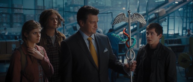 Behind the scenes of his UPS Store, Hermes (Nathan Fillion) shows Annabeth, Tyson, and Percy his staff with snakes and other fantastical things.