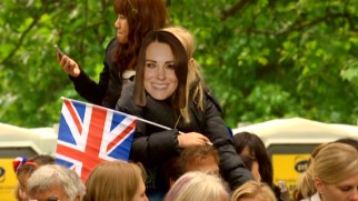 One young sidewalk spectator displays her support with a Flag of the United Kingdom and a cardboard Kate Middleton mask.
