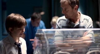 Father (John Simm) and son (Bill Milner) take a look at their family's newest member, a baby girl incubated for her health.