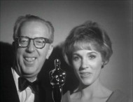 Composer Irwin Kostal and Julie Andrews hold up one of the film's many Oscars for the camera people at Fox Movietone News.