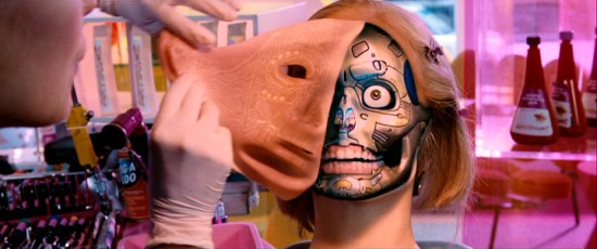 At a beautician's cosmetic shop, a surrogate's face peels right off to reveal the robotic skeleton below.