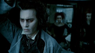 Brooding Sweeney Todd (Johnny Depp) looks out the window of the barbershop he's reclaimed from Mrs. Lovett (Helena Bonham Carter, rear).
