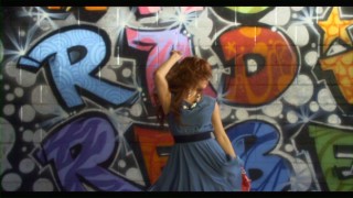 Debby Ryan dances in front of promotional graffiti in her "We Got the Beat" music video.