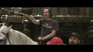 A clean-shaven, horseback Gary Oldman rides into a scene rehearsal in a "No Pictures" shirt.