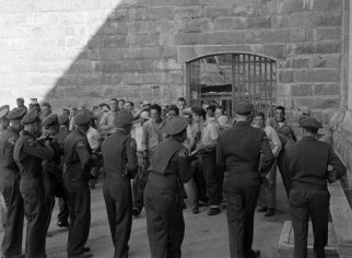 State police officers wielding guns move in on rioting prisoners brandishing homemade weapons in "Riot in Cell Block 11."