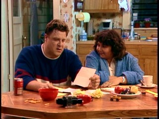 Dan (John Goodman) and Roseanne (Roseanne Barr) look it over in their kitchen.