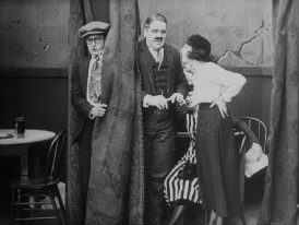 Harold Lloyd hides behind a curtain as his date (Bebe Daniels) catches her father with another woman in the 1919 short "Young Mr. Jazz."