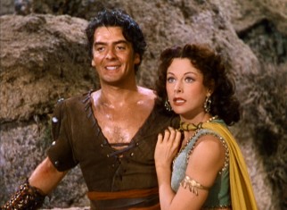Delilah (Hedy Lamarr) clings to the strong arms that Samson (Victor Mature) used to slay a lion.