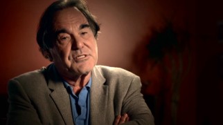 Though his in-theater PSA may be MIA, Oliver Stone still shares his voice in the making-of featurette "Finding the Truth."
