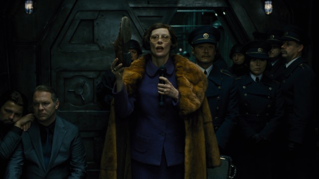 Minister Mason (Tilda Swinton) uses a shoe literally and metaphorically in a clumsy tail section speech.