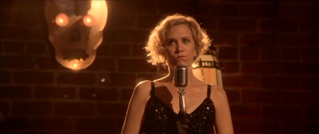 As in the previous "Spoils", Kristen Wiig serves as leading lady, this time playing lounge club singer Delores DeWinter.