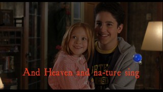 Lucy (Liliana Mumy) and Charlie (Eric Lloyd) smile as heaven and nature sing in "Christmas Carol-oke."