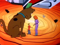 The journey inside a mirror takes the gang to a strange place where Scooby gets bigger, towering over Shaggy and Daphne.
