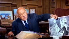 Producer/director/showman Cecil B. DeMille displays a photograph of Charlton Heston looking at Michelangelo's Moses statue in a 10-minute trailer for the movie.