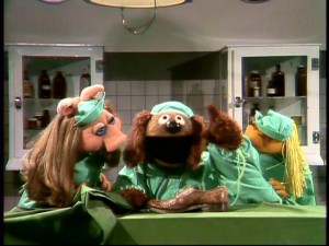 "Veterinarian's Hospital" is the continuing story of a former orthopedic surgeon who's gone to the dogs. Rowlf plays the absent-minded Dr. Bob, who examines a shoe here, with support from Piggy and Janice.