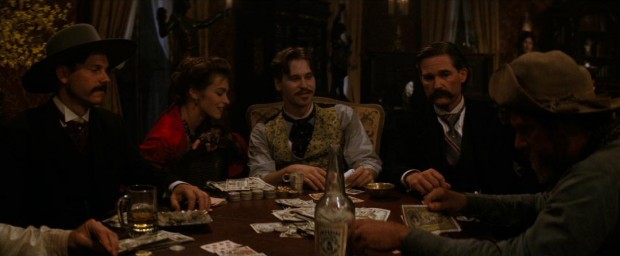 Doc Holliday (Val Kilmer) and his gal ("Big Nose") Kate (Joanna Pacula) are amused by the growing frustration of Ike Clanton (Stephen Lang, far right) in his poker game with Morgan (Bill Paxton) and Wyatt Earp (Kurt Russell).