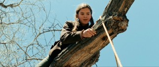 Mattie Ross (Hailee Steinfeld) tests her true grit with a tree climb and rope cut to identify a hanged man.