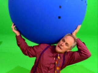 John Lithgow has got the whole world in his hands (plus a French Stewart sitting on top) in this green screen promo shoot seen in "A Glimpse Behind-the-Scenes."