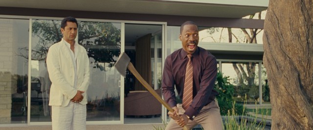 Dr. Sinja (Cliff Curtis) watches calmly as Jack McCall (Eddie Murphy) prepares to swing an axe at a tree to which his life has become connected.